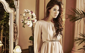 Брюнетка актриса Роксанна Макки стоит рядом с цветком орхидеи