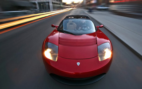 Красный электромобиль Tesla Roadster на трассе 