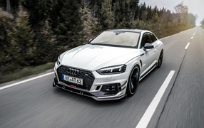 Белый автомобиль Audi RS5 2018 года на трассе у леса