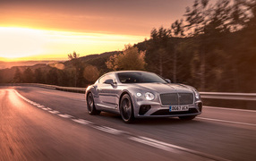Серебристый автомобиль Bentley Continental GT 2018 года на фоне заката