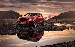 The new red car Bentley Bentayga V8, 2018 is reflected in the water