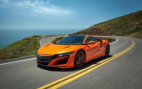 Оранжевый автомобиль Honda NSX на трассе под голубым небом