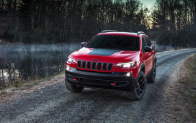 Red car Jeep Cherokee Trailhawk, 2019 on the road by the river