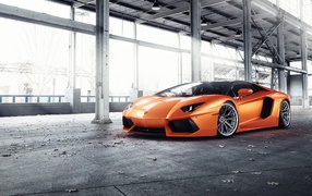 Оранжевый автомобиль Lamborghini Aventador под мостом