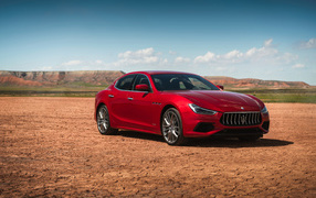 Красный автомобиль Maserati Ghibli на фоне голубого неба