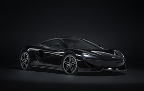 Черный спортивный автомобиль McLaren 570GT на сером фоне