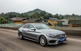 Серебристый автомобиль Mercedes-Benz C-Class на трассе