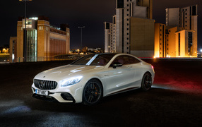 Белый автомобиль Mercedes AMG S 63 4MATIC Coupe, 2018 года на фоне города