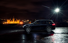 Черный автомобиль Porsche Cayenne в свете фонаря 