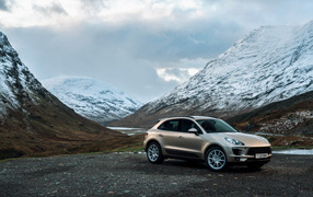 Off-road car Porsche Macan on a background of snow-capped mountains