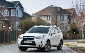 Белый автомобиль Subaru  Forester на улице у домов