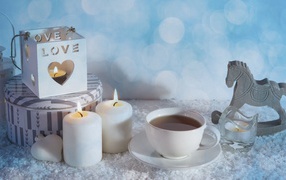 Свечи, чашка чая и фигура лошади на столе 