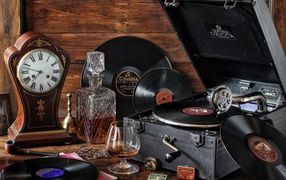 Старый граммофон с виниловыми пластинками, часами и коньяком на столе