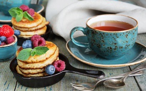 A cup of tea with pancakes with berries on the table