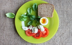 Легкий завтрак с помидорами, яйцом, кусочком хлеба и листьями базилика