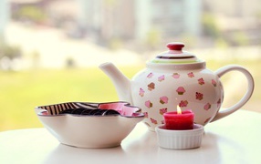 Чайник с печеньем орео и зажженной свечей на столе