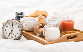 Appetizing breakfast in bed with alarm clock