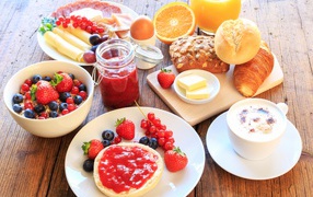 Аппетитный завтрак на столе с бутербродами, кофе и ягодами