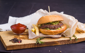 Аппетитный гамбургер с картофелем фри и кетчупом на столе