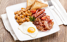 Бекон, яичница, фасоль и сосиски на тарелке к завтраку 