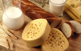 Сыр на столе с маслом, молоком и батоном 