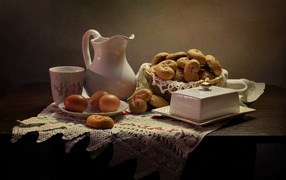 Вареные яйца на столе с кувшином, выпечкой и масленкой 