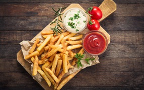 French fries with sauce and ketchup on the board