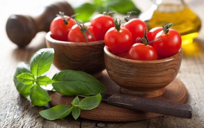 Fresh red tomatoes on a table in wooden bowls with basil
