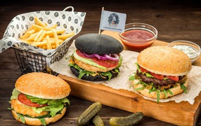 Гамбургеры с картофелем фри и солеными огурцами на столе 