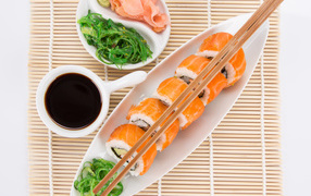 Japanese sushi on a table with soy sauce and ginger with salad