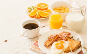 Сок, молоко, кофе, яичница и бекон на завтрак 