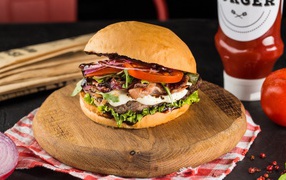 Большой аппетитный гамбургер на деревянной доске 