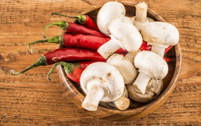 Mushrooms champignons in a wooden bowl with red pepper