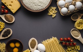 Pasta, eggs, spices and tomatoes on a gray background