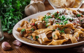 Паста с грибами, сыром и  зеленью на столе с чесноком 