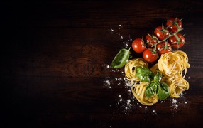 Pasta with tomatoes and basil leaves on a table