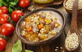 Перловый суп с сердечками на столе с помидорами 