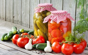 Соленья из огурцов и помидоров с овощами на столе
