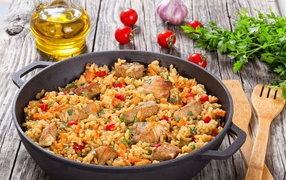 Плов с мясом на столе с помидорами и зеленью петрушки