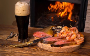 Smoked fish with shrimps by the fireplace with a glass of dark beer