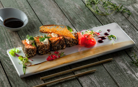 Sushi on a plate on a wooden table with sauce