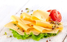 Тонко нарезанный сыр с листом салата и помидором