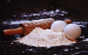 Два яйца, мука и скалка на столе