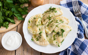 Вареники с зеленью на белой тарелке 