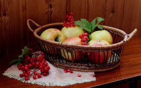 Beautiful apples in a basket on a table with berries of viburnum