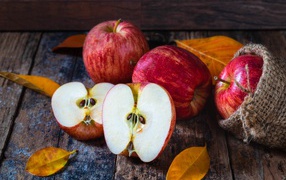 Красивые красные яблоки на столе с желтыми листьями