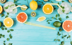 Цитрусовые фрукты на голубом столе с мятой и лимонадом