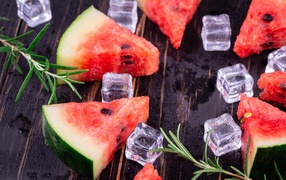 Pieces of watermelon on a table with ice and rosemary
