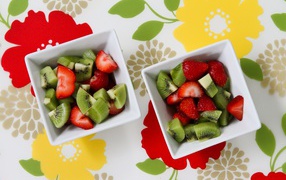 Salad with strawberries and kiwi berries in white plates on the table