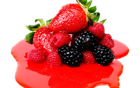 Strawberries, raspberries and blueberries with syrup on white background